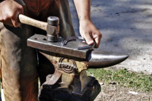 herrero trabajando la herradura con el martillo sobre el yunque